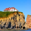 a house on the edge of the cliff overlooking the ocean