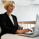 blonde businesswoman focused on working with her laptop in front of her in a modern office