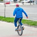 elderly man adeptly riding a unicycle on a city sidewalk