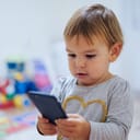 A baby using a phone, playing game or watching cartoons at home