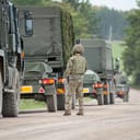 Convoy of British army Heavy Utility Trucks traveling down a dirt road in Wiltshire, UK