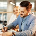 Man with signing a document in an office with a smile on his face