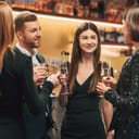 A group of stylishly dressed individuals celebrating a special occasion in a restaurant setting and drinking champagne.