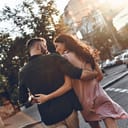 A couple hugging and walking down a street
