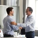 two men shaking hands, CEO congratulating a motivated employee for a promotion, modern office setting