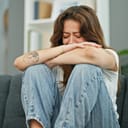 young woman sitting on a sofa and crying at home
