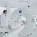 In Medical Laboratory Female Radiologist and Male Doctor Control and Monitor MRI or CT Scan with Female Patient Undergoing Procedure. High-Tech Modern Medical Equipment.