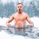 man taking a cold plunge into water during winter