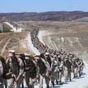 A long line of soldiers marching alongside a desert road