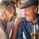 Senior, couple and laugh after comic joke together in restaurant for bonding time. Smile, man and woman in retirement laughing at funny conversation with love, happiness and comedy in cafe with wine