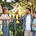 young family engaging in a warm conversation with an elderly couple by a fence outdoors