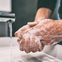 man washing his hands with soap and tap water in the sink