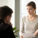 An irritated business woman talking with her colleague while holding a piece of paper