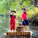 Children in pirate costumes playing with a treasure chest and swords on a raft in a river