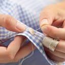 a woman sewing a button with a needle and some thread
