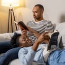 young couple, positioned comfortably on a couch in their living room, reading books