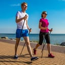 Two people with walking poles walking by the sea