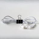 White headphones neatly fastened with a black binder clip on a white desk surface.