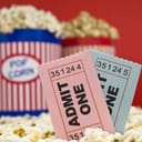 Two cinema tickets in front of buckets of popcorn