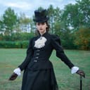 A sophisticated brunette lady in a strict elegant black suit of the 19th century strolls through an autumn park