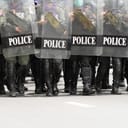 Police in full riot gear with shields forming a barricade