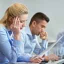 Two worried workers sitting at an office desk reviewing documentation