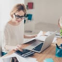 Happy and focused female accountant working with a computer and calculator in her office
