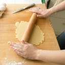Woman rolling dough on the table with a pin