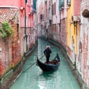 A gondolier in a Venetian canal between buildings