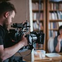 A director of photography holding a camera on the set, capturing scenes for a documentary.