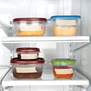 five containers of different sizes with leftovers in a fridge, labeled with blank tape and closed with colorful lids