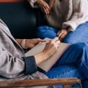 Person taking down notes while talking to another person
