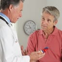 A doctor holding a model of a heart talking to a patient