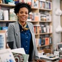 Happy African American saleswoman at bookstore checkout looking at camera.
