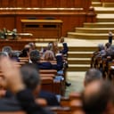 Members within the Romanian Parliament voting by raising their hands.