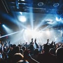 silhouette of concert crowd in front of bright stage lights. Dark background, smoke, concert spotlights, disco ball