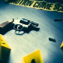a crime scene image with a gun, bullet shells and evidence markers on the floor
