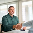 middle-aged businessman smiling and shaking hands with a recruiter during an office meeting