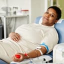 A happy woman donating blood at a donation center, smiling and looking at the camera.