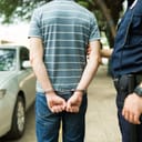 man with handcuffs being arrested by police, viewed from behind