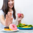 a young woman choosing a healthy salad and fruit juice over junk food