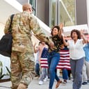 A soldier being greeted by a group of people carrying the American flag