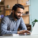 A man with a beard working on his laptop