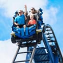 Young family having fun riding a rollercoaster at a theme park