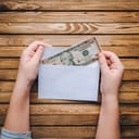 dollar bills in an envelope held by children's hands