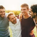 Joyful, four male buddies hugging each other and spending time outside.