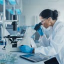 A Caucasian female scientist examines a sample under a microscope and analyzes a petri dish sample.