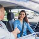 Young woman learning how to drive car together with her instructor. Driving school. Happy driving student. Woman passed. Young woman delighted having just passed her driving test