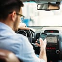Man in a car behind the wheel looking at his smartphone