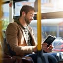 A man reading a book on a bus
